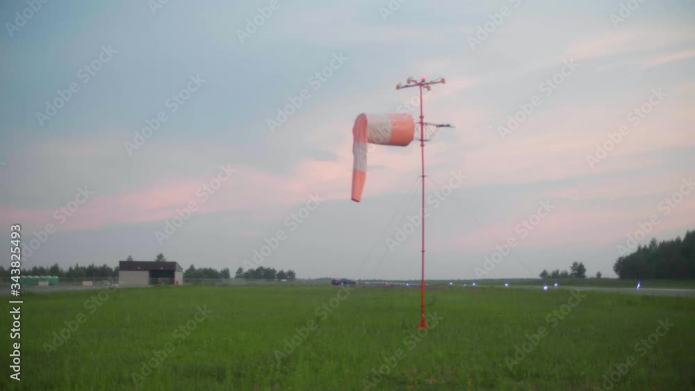 Weather vane in calm weather at the airport. A sports car rides behind Weather vane in calm weather at the airport. A sports car rides behind