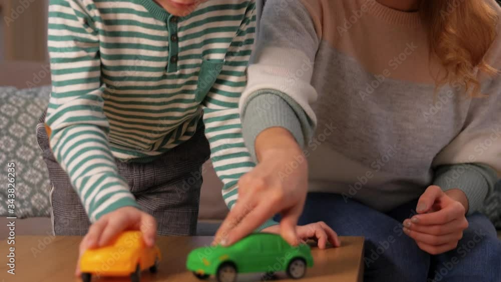 family, leisure and people concept - happy smiling mother and son playing with toy cars at home in evening family, leisure and people concept - happy smiling mother and son playing with toy cars at home in evening