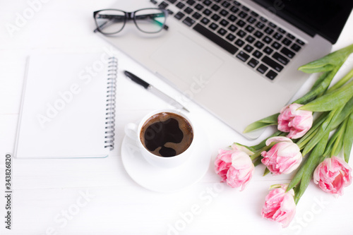 Pink tulips with a festive mood and coffee on white wooden boards.