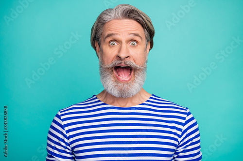 Close-up portrait of his he nice attractive cheerful cheery crazy grey-haired man wearing striped jumper opened mouth isolated over bright vivid shine vibrant green blue turquoise color background © deagreez