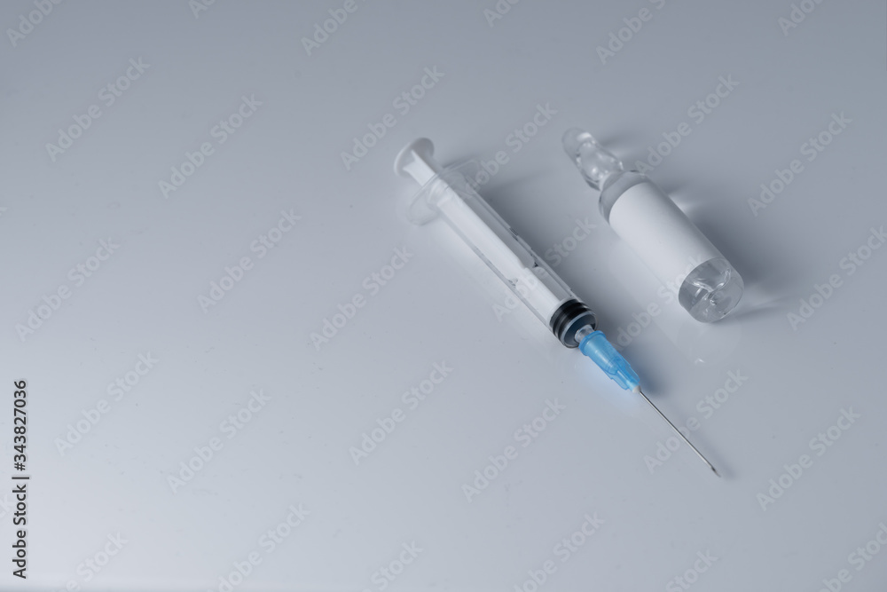 Medical vial for injection and a syringe,lays on the white table background Medical vial for injection and a syringe,lays on the white table background