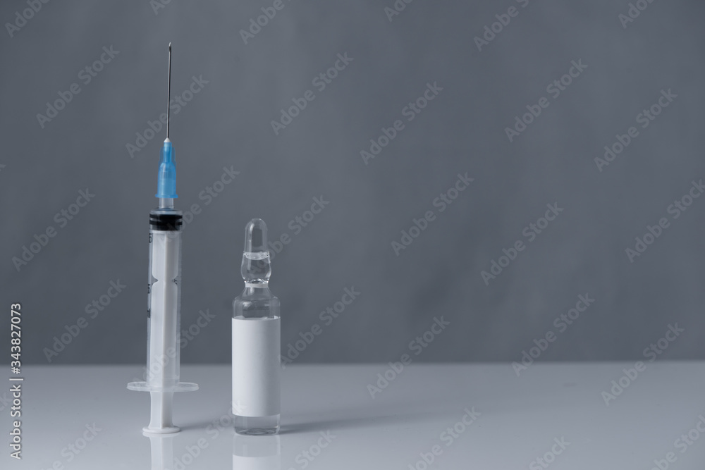 Medical vial for injection and a syringe,stay on the table on gray background Medical vial for injection and a syringe,stay on the table on gray background