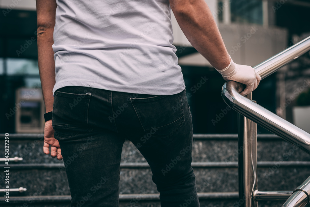 Male hand in a white latex medical glove on the railing..man wearing protective latex gloves touching railing outsid Male hand in a white latex medical glove on the railing..man wearing protective latex gloves touching railing outsid