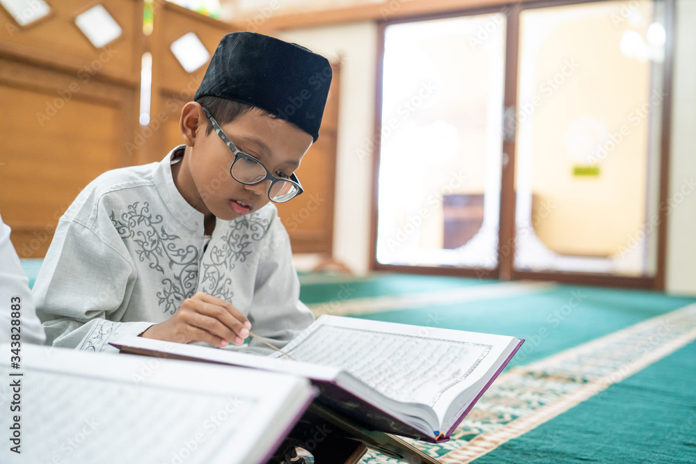 kid muslim reading quran in the mosque during ramadan kid muslim reading quran in the mosque during ramadan