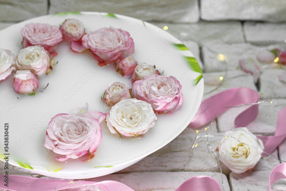 Dish with milk and small pink roses on a light background Dish with milk and small pink roses on a light background