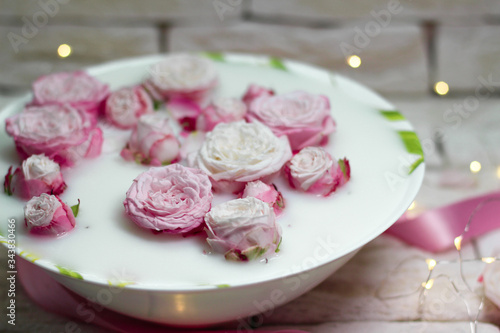 Pink roses in milk on a gray bricks background