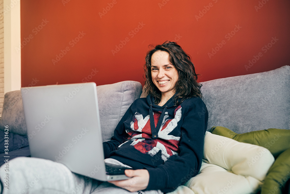 handsome woman sitting on couch with laptop and smiling to camera handsome woman sitting on couch with laptop and smiling to camera