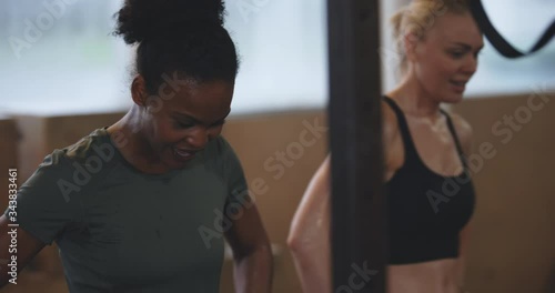 Smiling young African American woman sweating
after a working out on rings during an exercise
class at the gym
