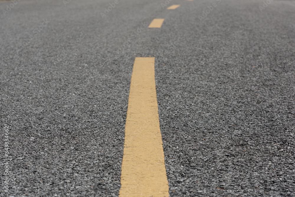 Obraz premium Yellow paint line on old asphalt bend