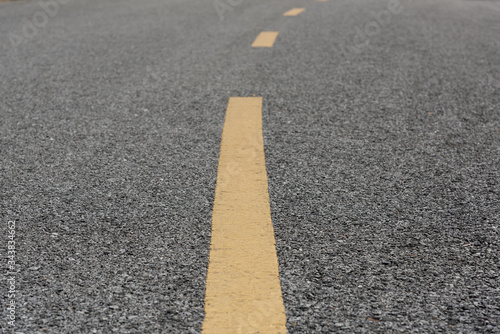 Yellow paint line on old asphalt bend