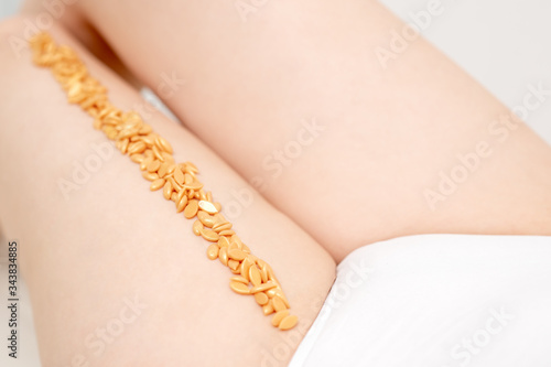 Wax golden beans on woman leg in row. Concept of depilation and epilation.