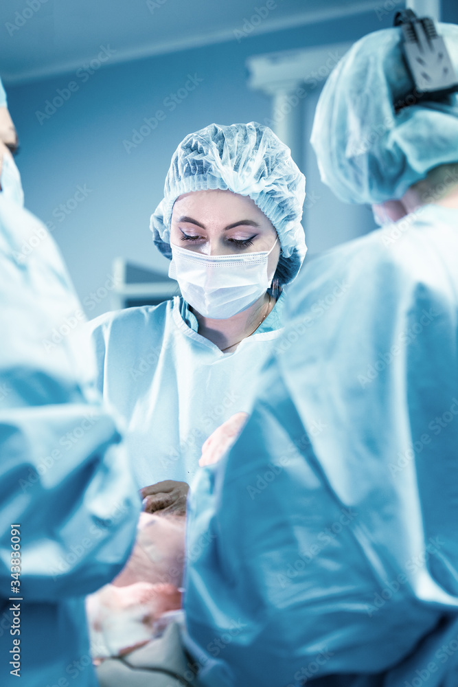 Female surgeon with operating assistants. Surgeons during work. Blue filter. Modern medicine with professional doctors. Female surgeon with operating assistants. Surgeons during work. Blue filter. Modern medicine with professional doctors.