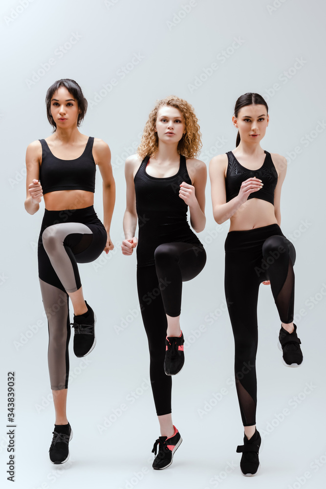 beautiful and multicultural women in sportswear exercising on white beautiful and multicultural women in sportswear exercising on white