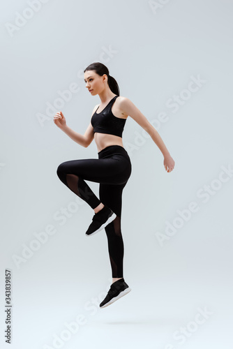attractive woman in black sportswear jumping on white