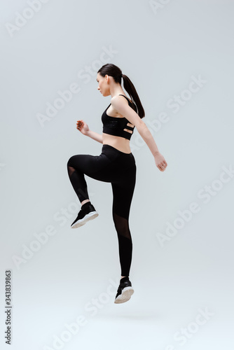 sportive woman in black sportswear exercising on white