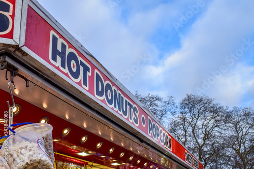 Hot donuts and popcorn sign at fairground, Clapham Common, UK