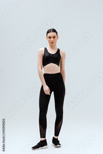sportive woman in black sportswear standing isolated on white