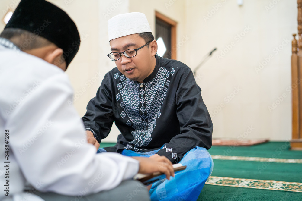 teacher is teaching muslim kid how to read holy quran in the mosque ...