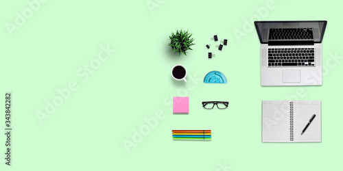Top view education desk and supplies, with copy space. Creative flat lay photo of workspace desk/Panoramic banner green background
