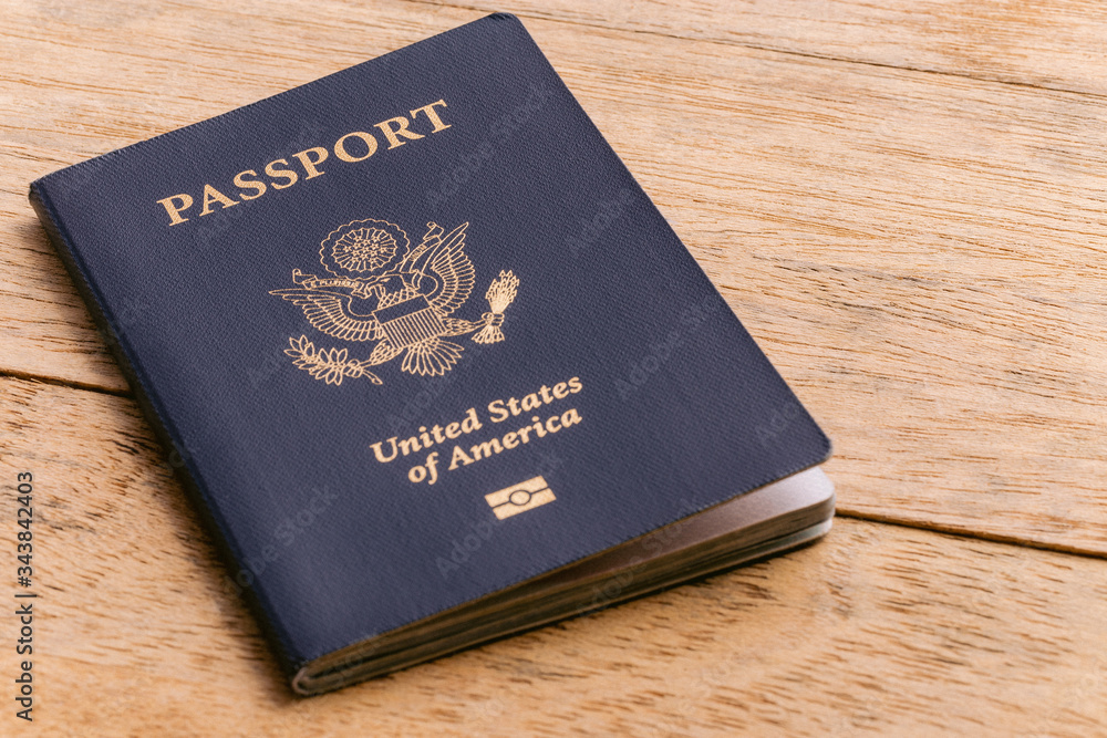 A blue American passport sitting on a wooden table A blue American passport sitting on a wooden table