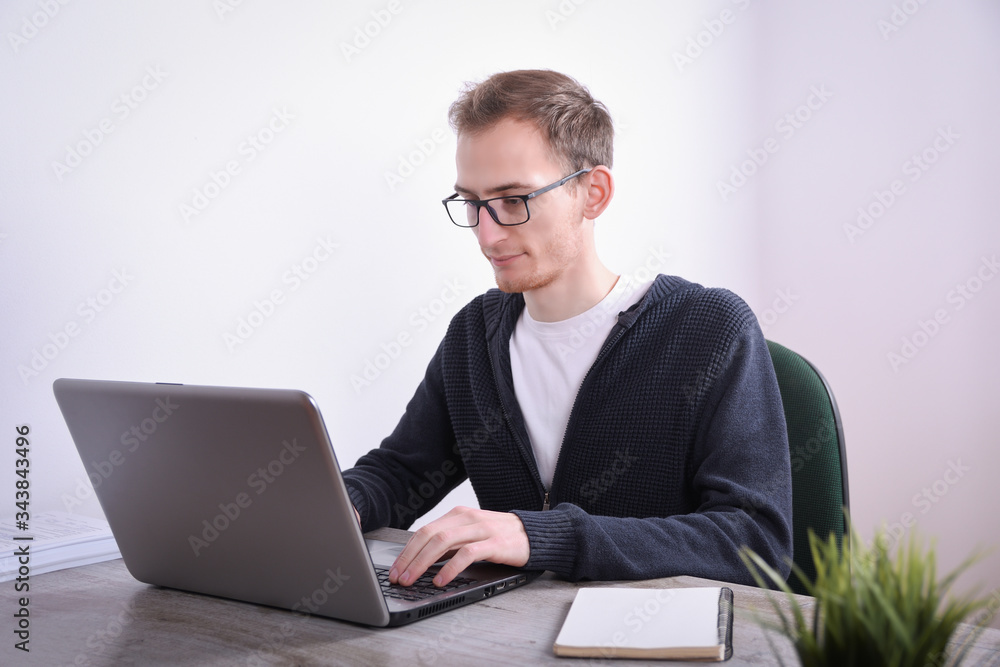Portrait of young business man sitting at his desk desktop laptop technology in the office.Internet marketing, finance, business concept Portrait of young business man sitting at his desk desktop laptop technology in the office.Internet marketing, finance, business concept