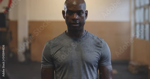 Fit young African American man in sportswear
sweating while standing in a gym after an intense workout session