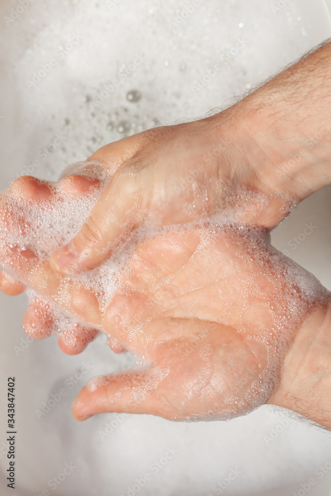 a man washes his hands over water with foam