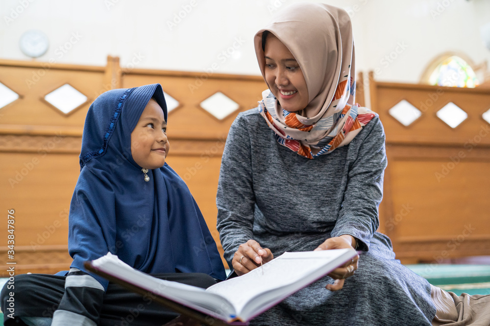 young muslim woman with kids reading quran together at the mosque young muslim woman with kids reading quran together at the mosque