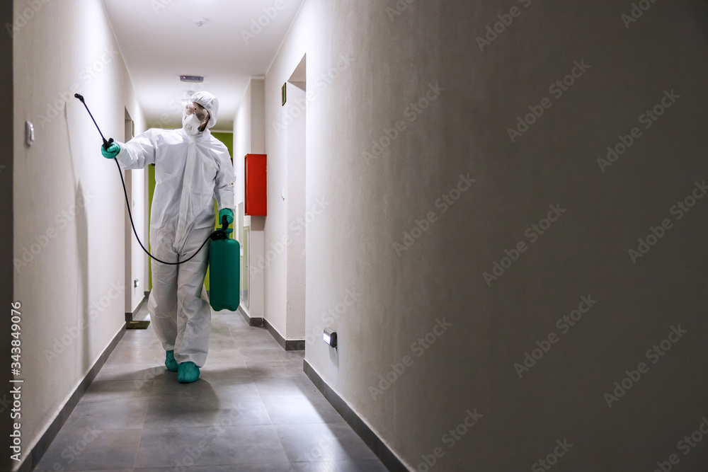 Worker in sterile suit and mask sterilizing hall of a building from corona virus / covid 19. Worker in sterile suit and mask sterilizing hall of a building from corona virus / covid 19.