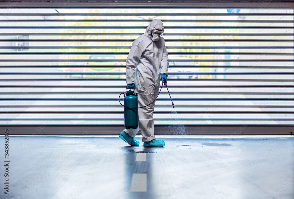 Man in protective suit and mask sterilizing garage from corona virus/ covid 19. Man in protective suit and mask sterilizing garage from corona virus/ covid 19.