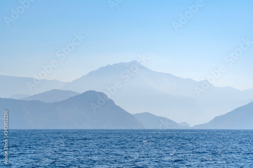 Sea and mountain view on a misty day. Blue degradation with copy space