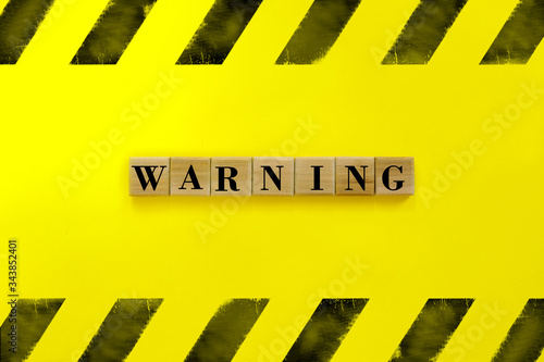The inscription on wooden cubes "Warning" on yellow background. World epidemic danger. Global pandemic.