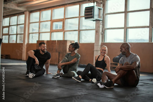 Smiling group of diverse friends talking on a gym floor