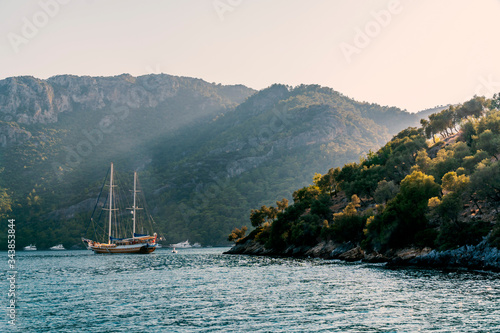 Photo Summer concept: A Turkish gulet and behind some luxury white yachts anchored at the Aegean sea with sun beam in background