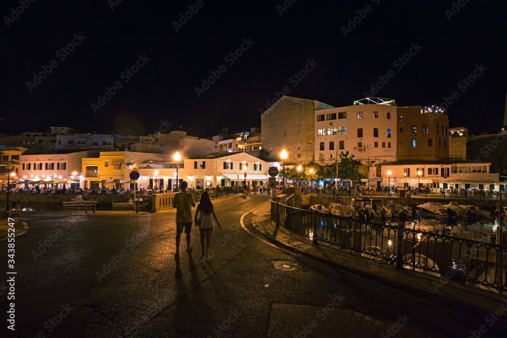 Night view of the harbor with its crowded clubs in Menorca in Spain.