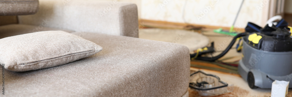 Sofa standing at domestic room with professional vacuum cleaner in background Sofa standing at domestic room with professional vacuum cleaner in background