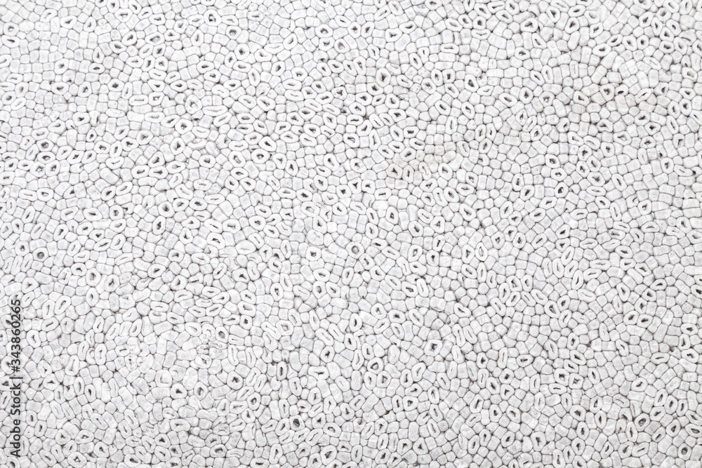 Background of gray color with a pattern of oval and round parts of polystyrene similar to sea pebbles pressed and used to trim or protect fragile parts close-up. Design panel or building material. Background of gray color with a pattern of oval and round parts of polystyrene similar to sea pebbles pressed and used to trim or protect fragile parts close-up. Design panel or building material.