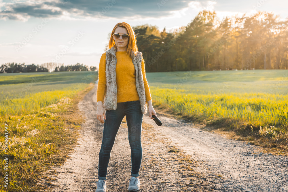 Red-haired woman in dark glasses on a dirt road