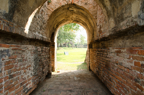 Ancient fotress on the bank of Chao Phraya river, green park view through the old tunnel at Ayutthaya, Thailand.