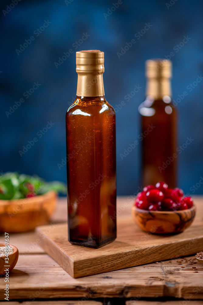 Two bottles of olive oil with bowl of olives and salad on wooden board Two bottles of olive oil with bowl of olives and salad on wooden board