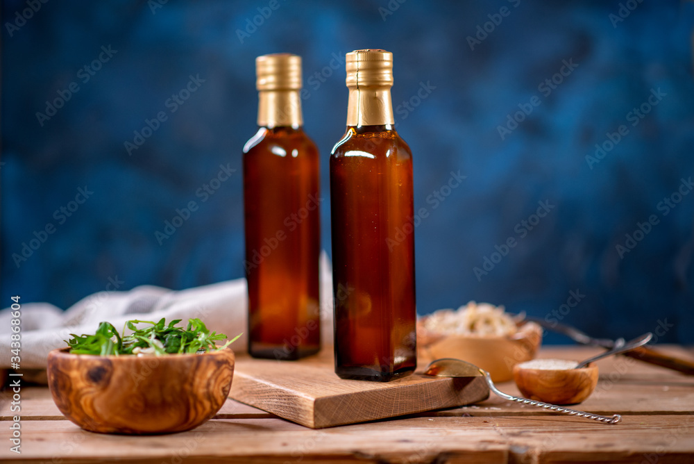 Two bottles of olive oil with bowl of olives and salad on wooden board Two bottles of olive oil with bowl of olives and salad on wooden board