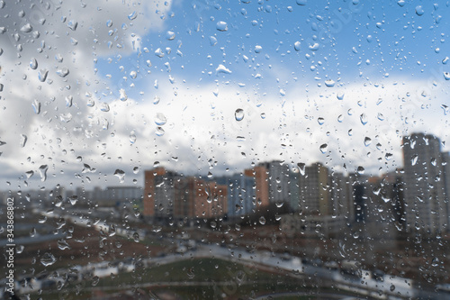 Drops of water or rain drops on window glass with blur buildings background.