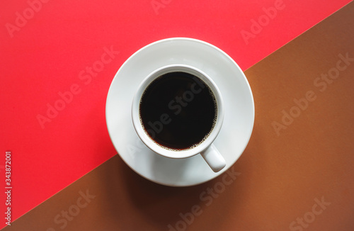 Cup of black coffee on abstract red and brown background with copy space