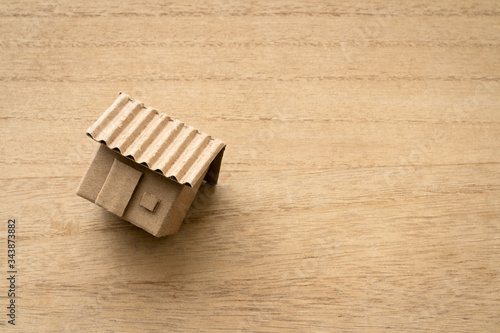 Model of cardboard house isolated on wooden background for building, mortgage, real estate or buying a new home concept. Lay flat view.