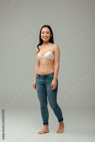 happy overweight asian girl standing on grey
