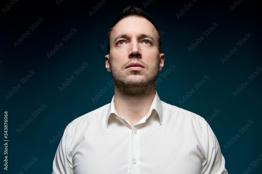 Young unshaven man in a white shirt looks into the void Young unshaven man in a white shirt looks into the void