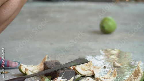 Green fresh coconut peeling and shelling with heavy chop knife for juice.