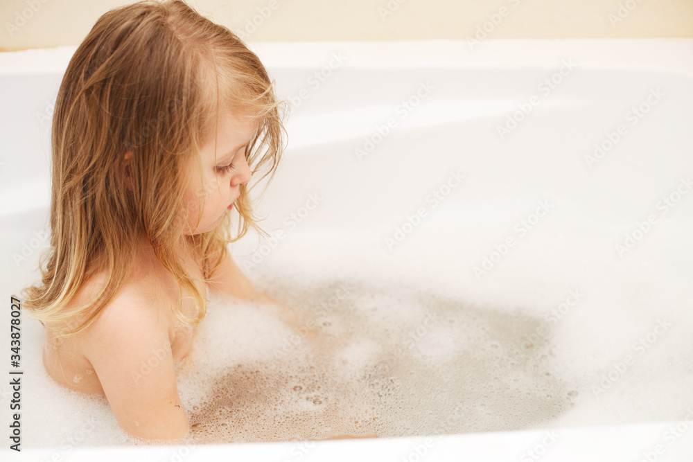 Funny little baby girl with blond hair playing with foam in a bath tub. girl takes a bath Funny little baby girl with blond hair playing with foam in a bath tub. girl takes a bath