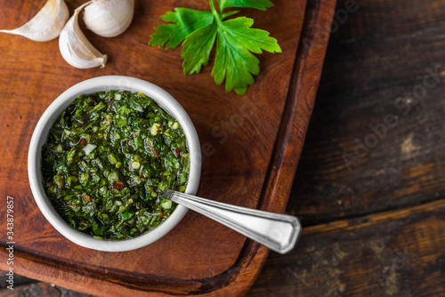 Traditional Argentinian chimichurri sauce against wooden backgroundv photo