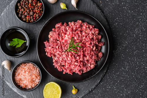 Fresh minced meat ground beef on a black plate against stone background photo